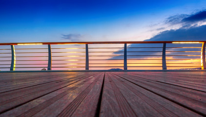 Wooden platform and railing on the background of a bright sunset, abstract background