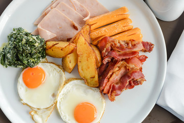 Breakfast consists of eggs, bacon, sausage, bacon, potato and spinach with cheese. delicious on the morning
