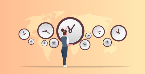 Businesswoman pointing on wall with clocks different