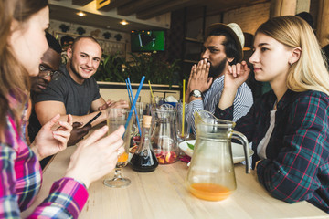 Meet young attractive people in the cafe. Friends chat, have fun, drink cocktails and eat