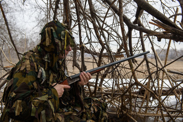 A hunter in a hut from the branches looks out for prey