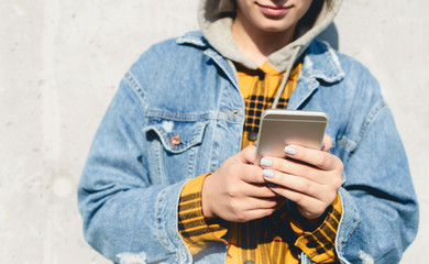 Fototapeta premium Young female using his smartphone on the street. Woman texting on her phone