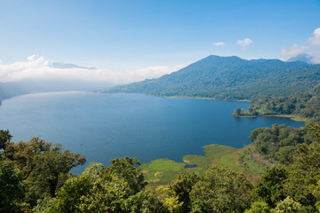 View of Lake Buyan on Bali island, Indonesia. It's Bali’s second biggest lake. Volcanoes have created and shaped this island and producing rich soils enabling a lush forest to grow.