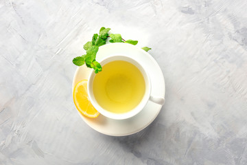 Obraz na płótnie Canvas A photo of a cup of tea with lemon and mint, shot from the top with a place for text