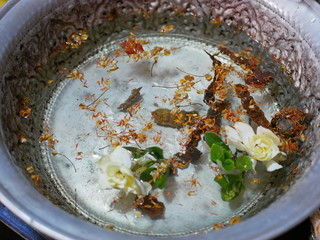 Big cup ( salung ) filled with holy turmeric water along with Cape Jasmine flowers and sompoi, Acacia concinna, for Rod Nam Dam Hua ceremony, paying respect to the elders, during Songkran festival 