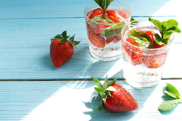 refreshing summer drinks detox water with fresh strawberries  and mint on blue wooden surface, table, background. Copy space