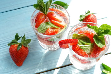 refreshing summer drinks detox water with fresh strawberries  and mint on blue wooden surface, table, background. Copy space