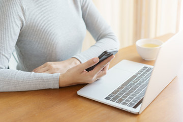 The hand of Asian women are using smartphone and computer in the office. Young women are using phones in social networks.