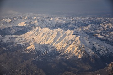 Aerial view from airplane of the Wasatch Front Rocky Mountain Range with snow capped peaks in winter including urban cities of Provo, Farmington Bountiful, Orem and Salt Lake City. Utah. United States