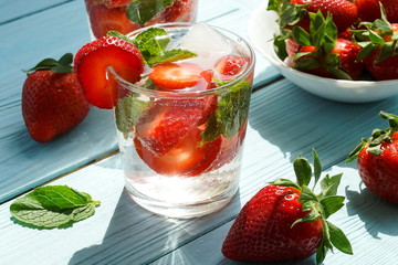 refreshing summer drinks with fresh strawberries  and mint on blue wooden surface, table, background. Copy space