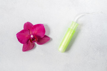 Cotton tampon with orchid on light grey background. Concept of critical days, menstruation or woman's health. Top view, flat lay.