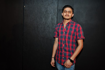 Obraz premium Asian man in checkered shirt against dark background.