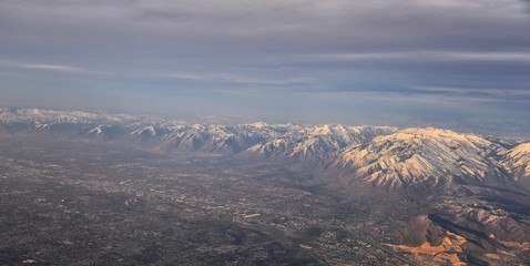 Aerial view from airplane of the Wasatch Front Rocky Mountain Range with snow capped peaks in winter including urban cities of Provo, Farmington Bountiful, Orem and Salt Lake City. Utah. United States
