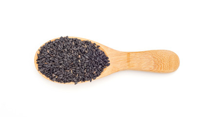 Black sesame seeds in a spoon on a white background.