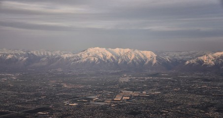 Aerial view from airplane of the Wasatch Front Rocky Mountain Range with snow capped peaks in winter including urban cities of Provo, Farmington Bountiful, Orem and Salt Lake City. Utah. United States