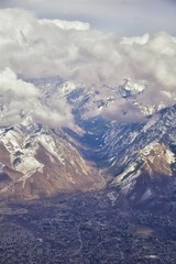 Fototapeta na wymiar Aerial view from airplane of the Wasatch Front Rocky Mountain Range with snow capped peaks in winter including urban cities of Provo, Farmington Bountiful, Orem and Salt Lake City. Utah. United States