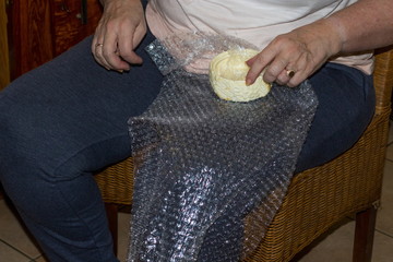 Adult person wrapping household objects and packing it in a cardboard box