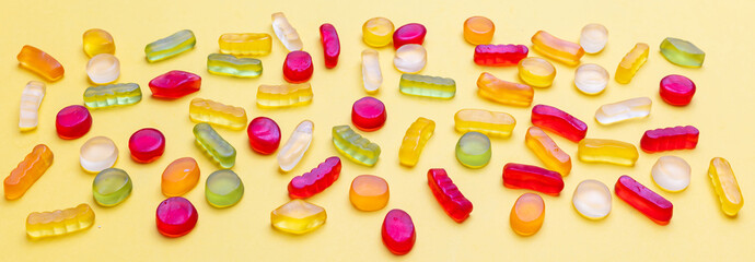 Colorful jelly candies assortment on yellow color background, banner, closeup view