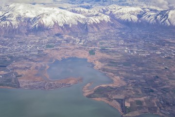 Fototapeta na wymiar Aerial view from airplane of the Wasatch Front Rocky Mountain Range with snow capped peaks in winter including urban cities of Provo, Farmington Bountiful, Orem and Salt Lake City. Utah. United States