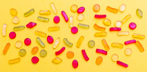 Colorful jelly candies assortment on yellow color background, top view