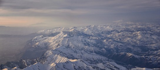 Naklejka na ściany i meble Aerial view from airplane of the Wasatch Front Rocky Mountain Range with snow capped peaks in winter including urban cities of Provo, Farmington Bountiful, Orem and Salt Lake City. Utah. United States