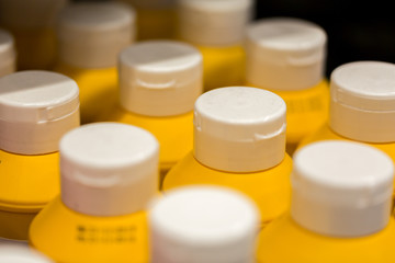 Close up / macro of plastic bottles with white cap and yellow body. The bottles contain mustard.
