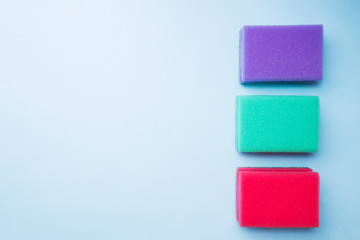 Cleaning colors sponges and brushes on blue background. Home cleaning concept. Top view, copy space.