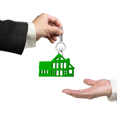 Buying or renting green energy house concept. One man hand giving silver key with green grass house shape keyring to another, isolated on white background.