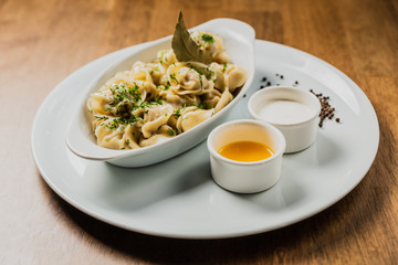 Meat dumplings or pelmeni served with sour cream and dill