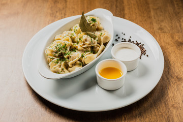 Meat dumplings or pelmeni served with sour cream and dill