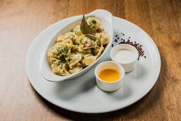 Meat dumplings or pelmeni served with sour cream and dill