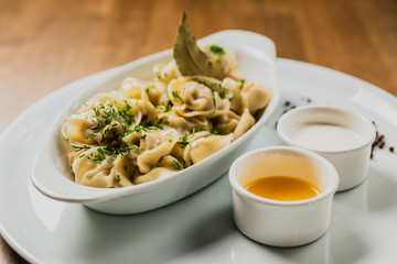 Meat dumplings or pelmeni served with sour cream and dill