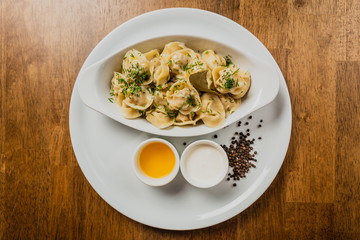 Meat dumplings or pelmeni served with sour cream and dill