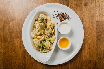 Meat dumplings or pelmeni served with sour cream and dill