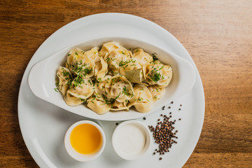 Meat dumplings or pelmeni served with sour cream and dill