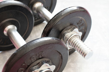 Obraz premium Fitness or bodybuilding concept background. Product photograph of old iron dumbbells on grey, conrete floor in the gym.