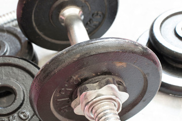 Fototapeta premium Fitness or bodybuilding concept background. Product photograph of old iron dumbbells on grey, conrete floor in the gym.