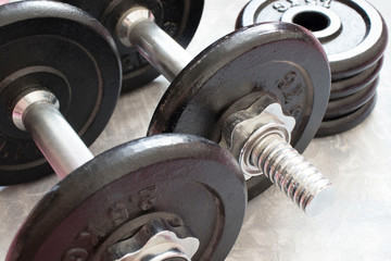 Obraz premium Fitness or bodybuilding concept background. Product photograph of old iron dumbbells on grey, conrete floor in the gym.