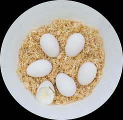 Six Bantam white eggs on brown Sawdust with one being crack egg, which they are in a round white bowl, isolated on black background.