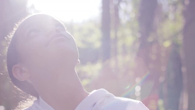 Beautiful young child looking around a forest in the sunlight, in slow motion 