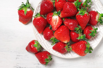 Fresh strawberries in plate on white wood