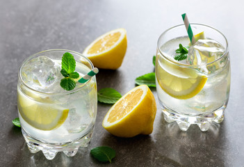 glass of fresh drink with ice and lemon on slate background