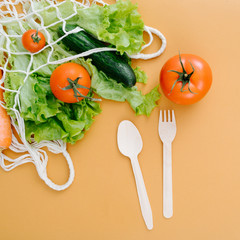 Spoon, fork and vegetables in a string bag