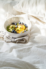 Healthy vegan breakfast in bed. Granola with avocado, superfoods, berries and fruits in a white bowl.