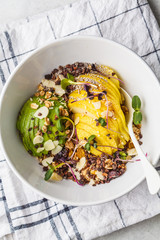 Healthy vegan breakfast. Granola with avocado, superfoods, berries and fruits in a white bowl, top view.