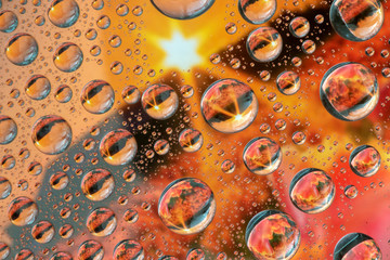 Many water droplets reflecting a sunset
