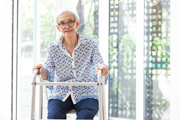 Asian senior woman sitting with walker during rehabilitation, elderly woman wear glasses,smiling...