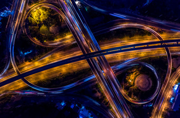 Road interchange in the city at night with vehicle car light movement, Aerial view.