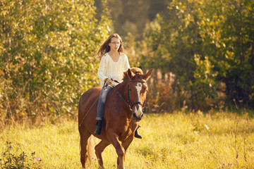Young girl goes sorrel horse riding