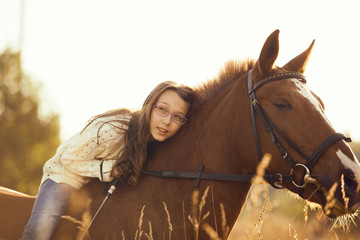 Fototapeta premium Young girl with sorrel horse in field